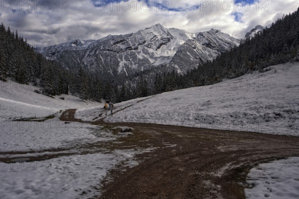 Picturesque view of snow-covered mountains on a path in front of dramatic clouds, Krün, Bavaria,