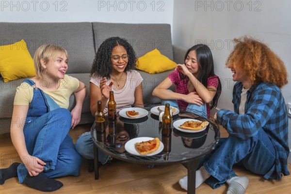 Group of young multi ethnic friends laughing and eating pizza and drinking beer, sitting around a