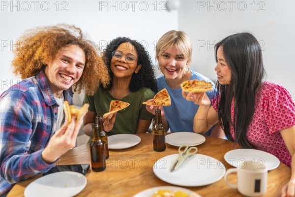 Four young, cheerful friends of diverse backgrounds enjoying pizza and beer together at home,
