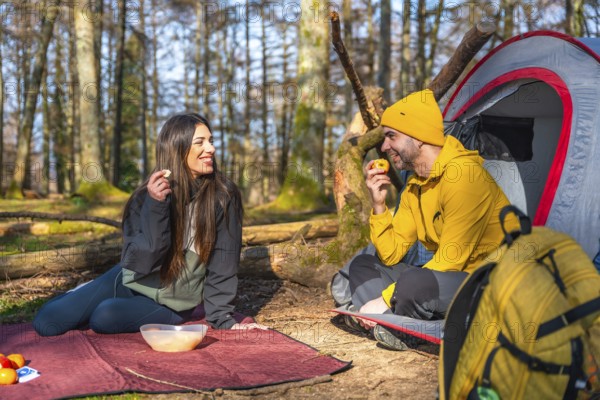 Hikers enjoying a healthy snack of fruit during a camping trip in a sunny forest, promoting a