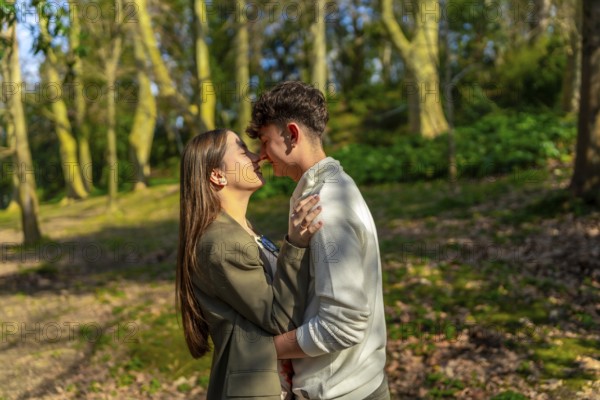 Young couple embracing and sharing a tender moment in a beautiful forest, surrounded by trees and