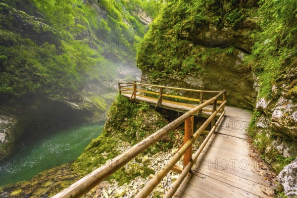 Breathtaking view of wooden walkway over stunning emerald river flowing through vintgar gorge near