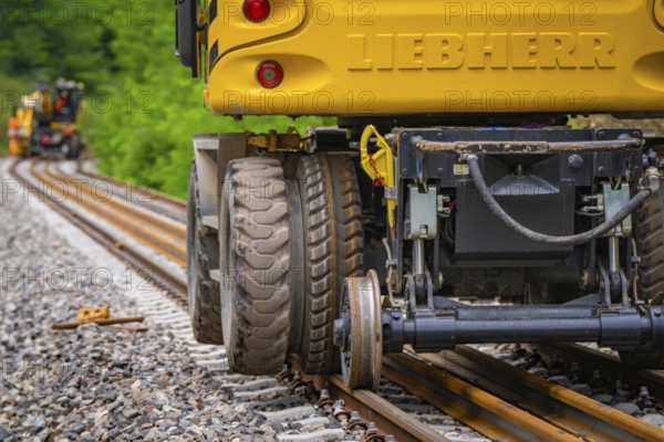 Close-up of the tyres of a yellow construction machine on rails, track construction, Hermann