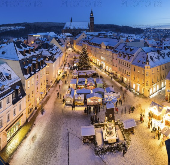 The snow-covered Christmas market with St Wolfgang's church seen from the town hall tower,