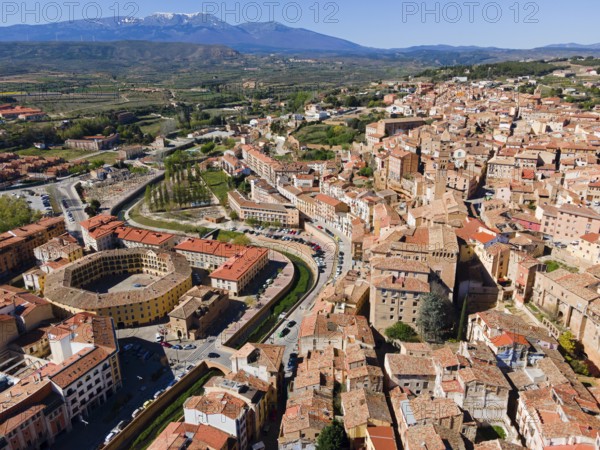 Aerial view of a historic town with tiled roofs and a hilly landscape in the background, aerial