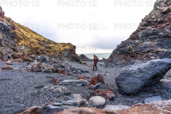 A tourist man on Djupalonssandur beach on the Snaefellsnes peninsula in winter in Iceland
