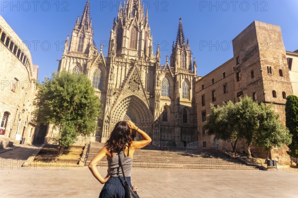 Young woman shielding her eyes from the sun while contemplating the majestic barcelona cathedral in