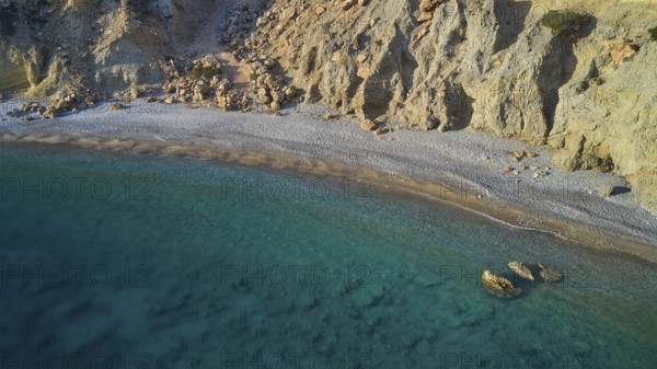Quiet stretch of beach with rocky coastline and crystal clear water in turquoise blue colour, drone