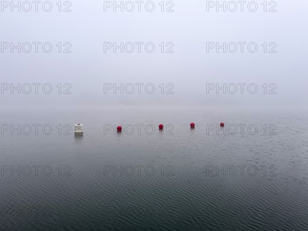 Buoys for water sports in dense fog on Lake Baldeney in Essen, foggy weather in winter, North