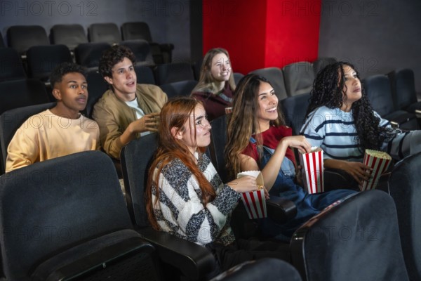 Group of diverse friends enjoying a film at the movie theater, eating popcorn and having fun
