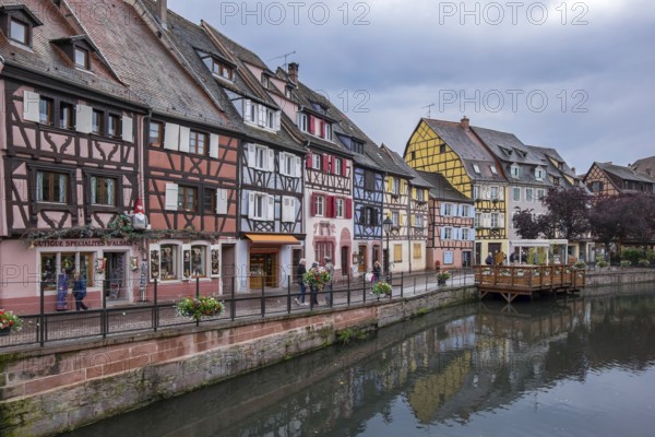 Colourful half-timbered houses on a quiet canal in a historic old town with a cloudy sky, Petite