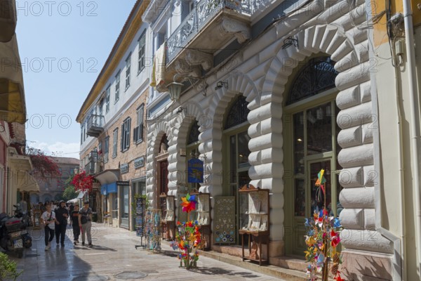 Lively shopping street with historic buildings, shop windows and colourful windmills under a blue