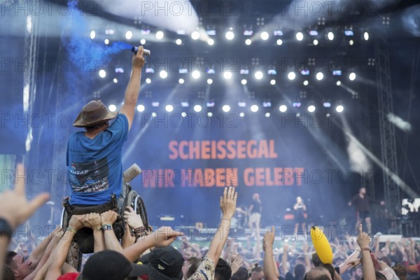 A wheelchair user with pyro in his hand is carried over the audience during the performance of the
