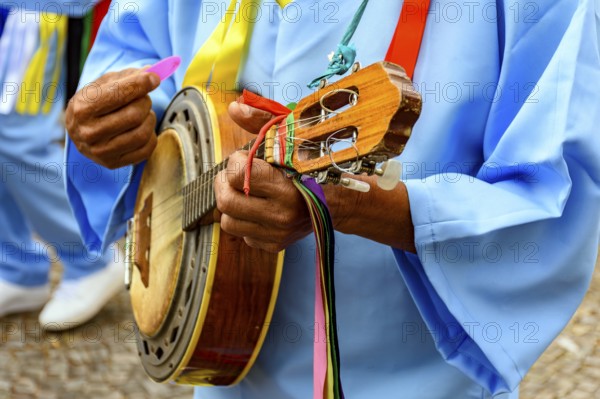 Hands of banjoist on the streets of Brazil wearing colorful clothes during a traditional religious
