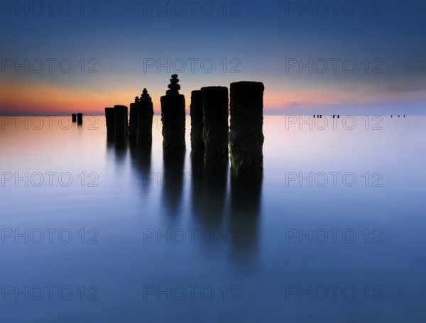 Stone pyramids on old groynes with algae in the water on the beach of the Baltic Sea, long exposure
