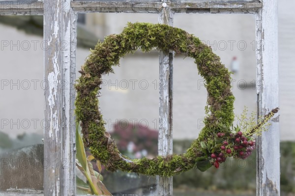 Door or window wreath made of natural materials in front of an old window, decoration, North