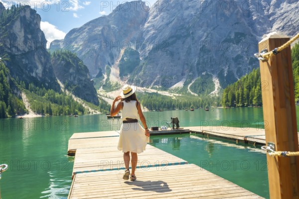Tourist walking on a wooden pier, enjoying the scenic view of lake braies and the surrounding