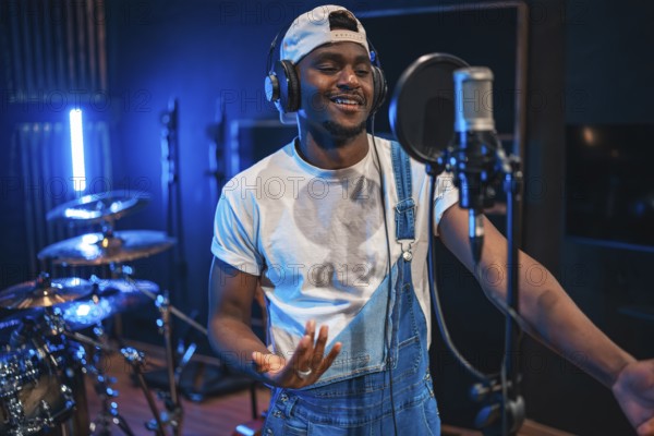 Young, happy african american male artist singing passionately in a professional music recording