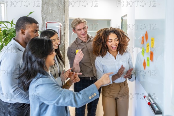 Diverse colleagues brainstorming and planning using colorful sticky notes on a whiteboard,