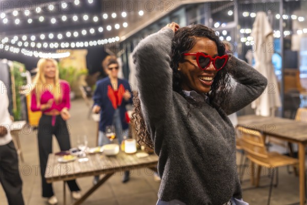 Funny latin woman with heart-shaped sunglasses and casual winter clothes dancing next to friends at