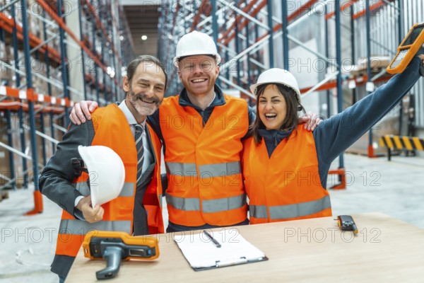 Warehouse workers and their manager are hugging each other, celebrating a successful logistics