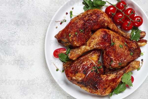 Grilled fried chicken legs, served, with fresh cherry tomatoes, and herbs, on a white plate,