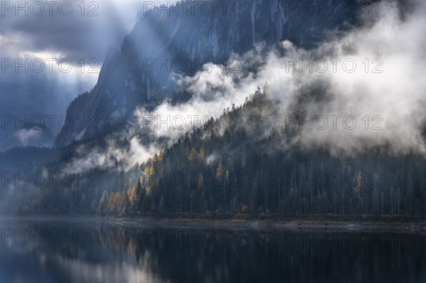 The Vordere Gosausee in autumn with a view of the Gosaukamm. Rays of sunshine shine through the