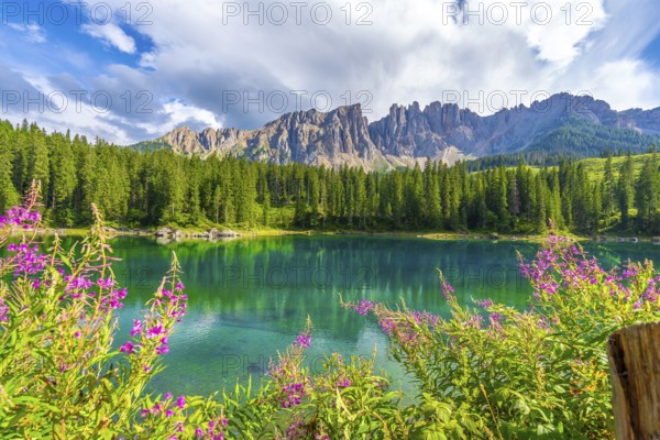 Wonderful aerial view of lake carezza reflecting latemar mountain range in the dolomites on a sunny