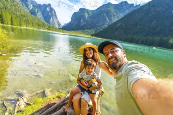 Happy family enjoying summer vacation taking a selfie at lake dobbiaco with the dolomites in the