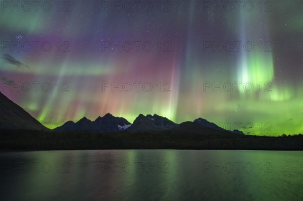 Northern lights over Bergen in the Lyngen Alps, reflection on the lake, Troms og Finnmark, Norway,