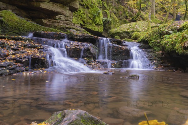 Small waterfall in a moss-covered forest with autumn leaves, Monbachtal, Bad Liebenzell, district
