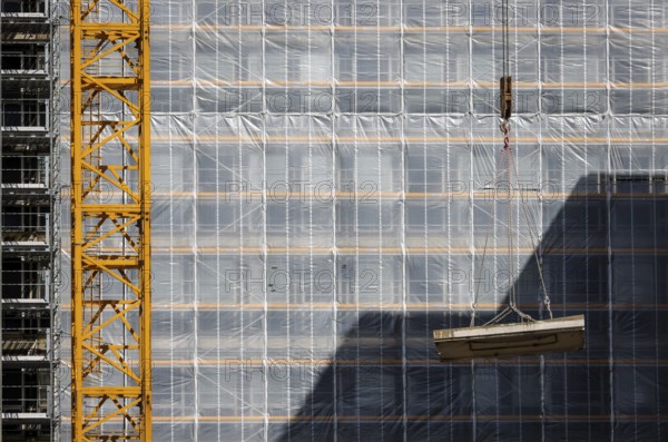 Essen, North Rhine-Westphalia, Germany - Construction crane lifts concrete section in front of