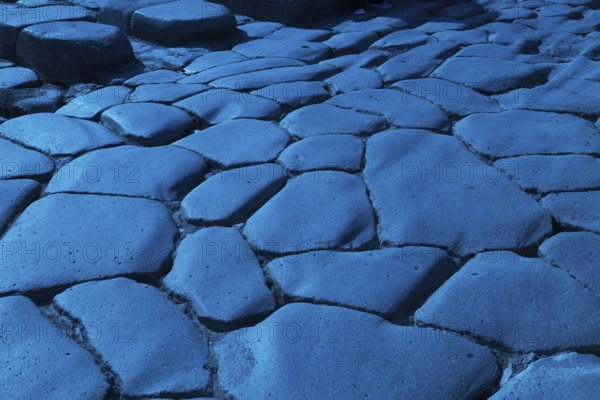 Close-up of large grey smooth and worn lava stones in a street at the ancient ruins of Pompeii,