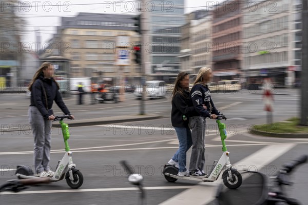 Young woman, two of them on an e-scooter, in the city centre, here at Neumarkt in Cologne, parked