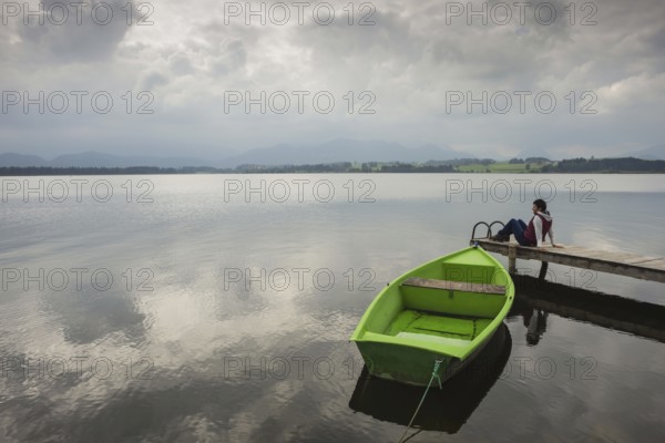 Woman 50-60, wooden jetty, green rowing boat, Hopfensee, Hopfen am See, near Füssen, Ostallgäu,