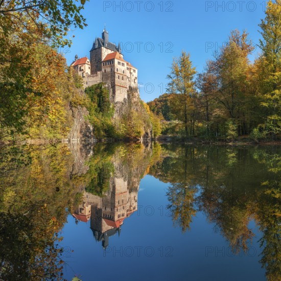 Kriebstein Castle near Mittweida surrounded by colourful forest in autumn, reflection in the river