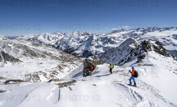 Ski tourers descending from the summit of the Madritschspitze, mountain panorama with snow-covered