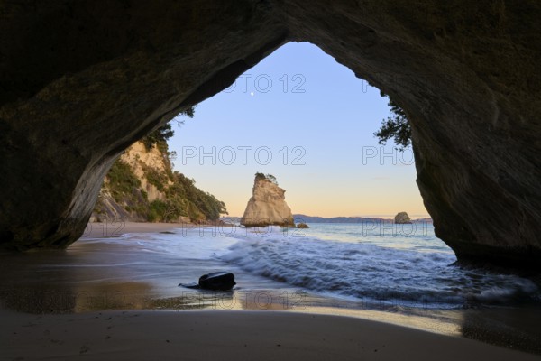 Cave opening shows a calm sea scene with rock formations in the twilight, Cathedral Cove,