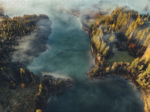 Autumn sunrise in the foothills of the Alps with fog at Illasbergsee and Forggensee near Halblech