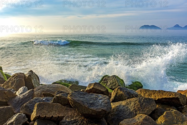 Waves crashing against the rocks of the Barra da Tijuca breakwater during dawn in Rio de Janeiro