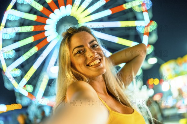 Personal point of view of a beauty happy woman taking selfie in an amusement park at night with a