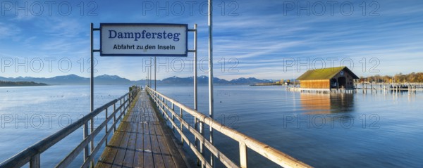Steamer jetty and boathouse on Lake Chiemsee in autumn in the morning light, behind the Chiemgau