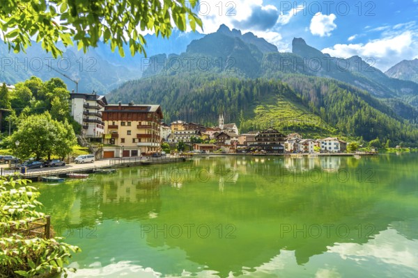 Tranquil summer scene of alleghe village reflecting on the emerald waters of lake alleghe, nestled