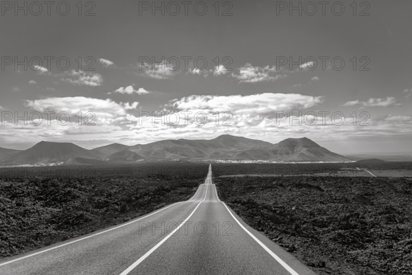 Empty endless country road through volcanic landscape, typical lava fields, Timanfaya National