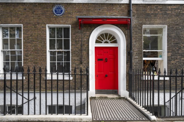 Red entrance door in a brick building with a cast-iron fence, Charles Dickens Museum, 48-49 Doughty