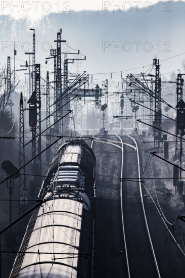 Deutsche Bahn AG tracks backlit with goods train. Overhead line, signals and infrastructure.