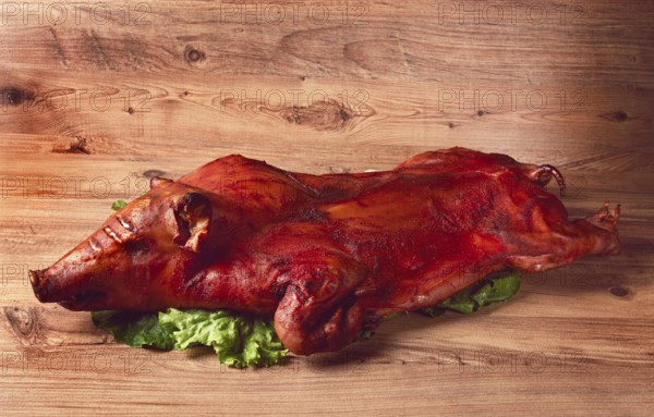 Baked, fried piglet, on a wooden table, no people, The whole piglet is baked and served on the
