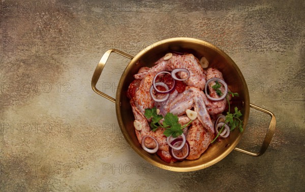 Chicken wings, in a brass saucepan, ready for cooking, grilling or baking, in a home kitchen, no