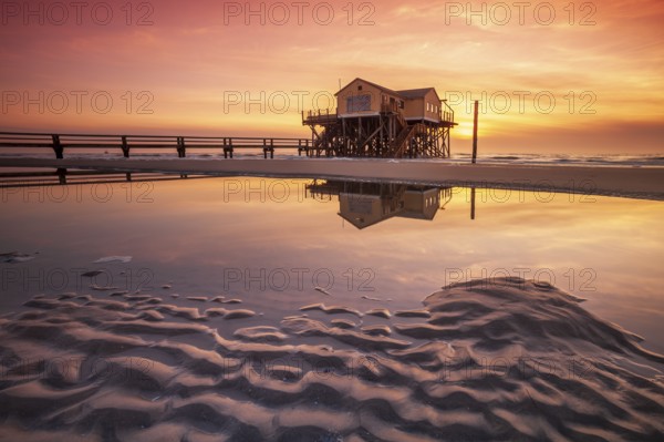 Stilt house on the beach at sunset, reflection in tidal pool, St. Peter-Ording Schleswig-Holstein