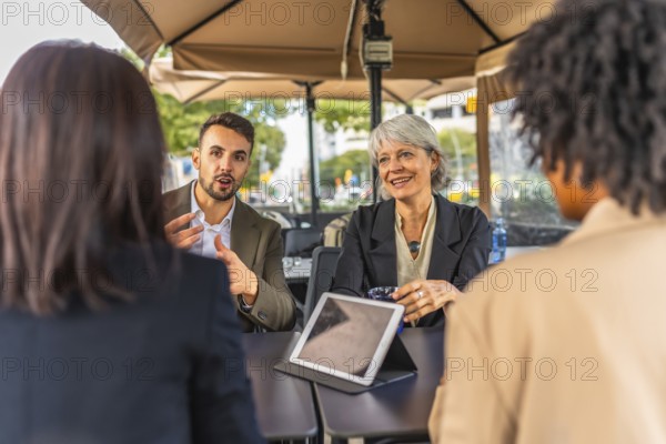 Business team talking and using digital tablet during meeting in a cafeteria